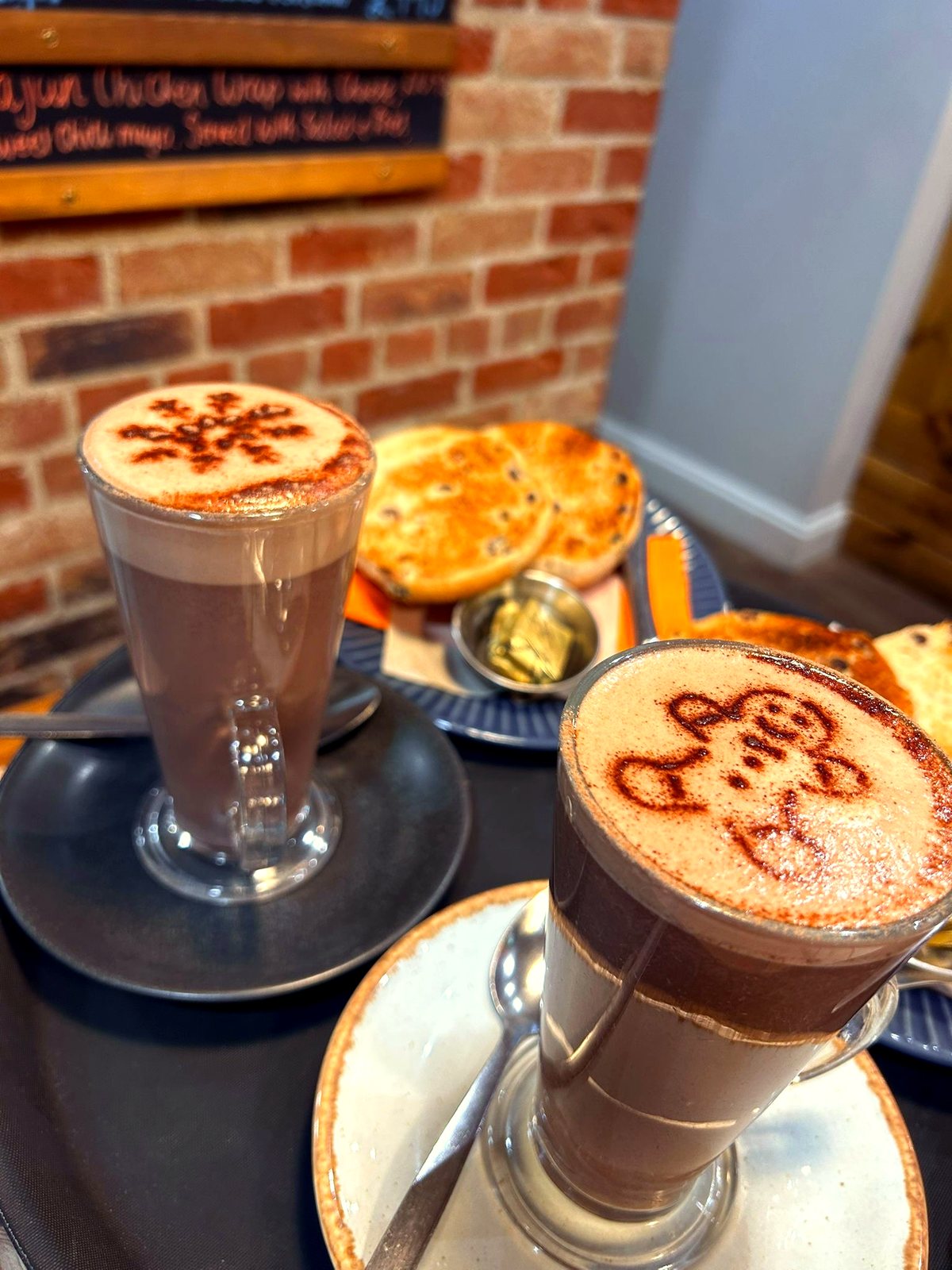 Two hot chocolates with cocoa art and toasted teacakes