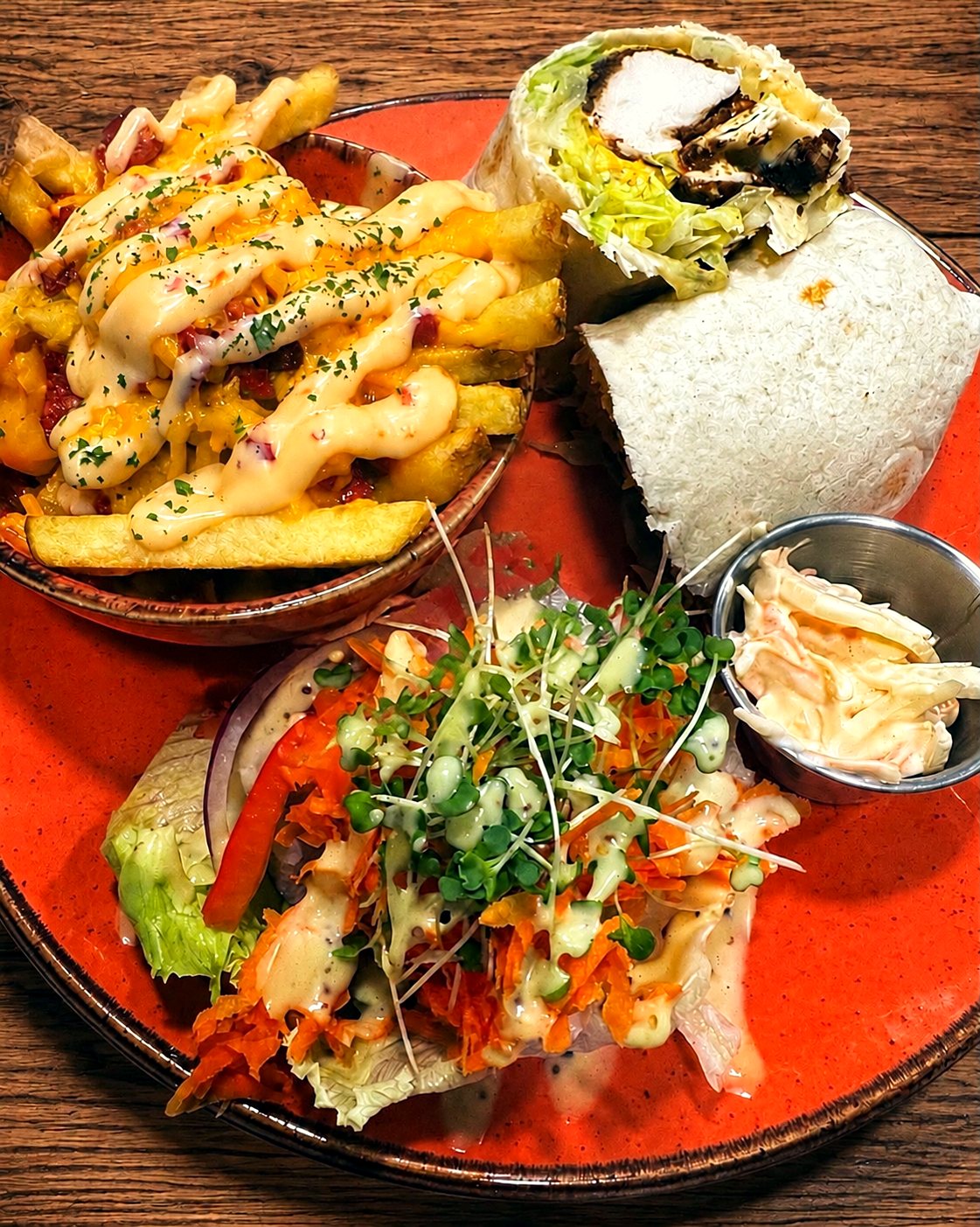 Homemade cajun chicken wrap with a bowl of cheese-loaded dirty fries