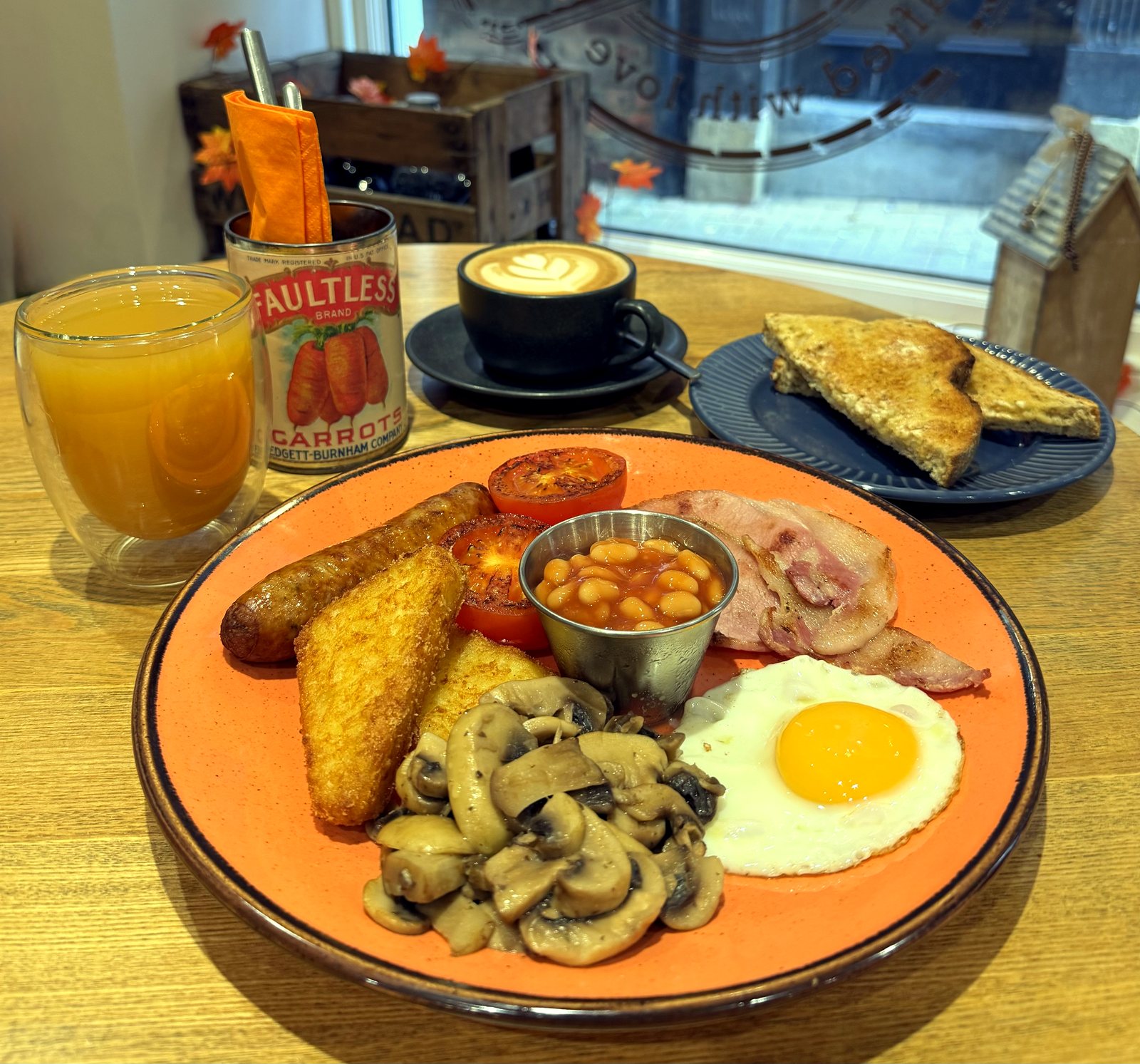 Full English breakfast with sausage, hash brown, fried egg, mushrooms, beans, bacon, tomato and toast